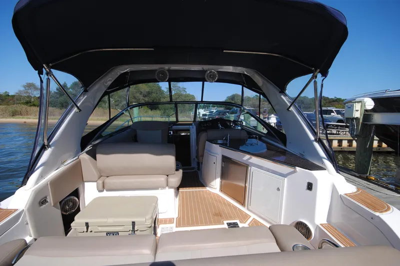 Slide: The Image of 2015 Regal 32 Express boat interior with seating, canopy, and dashboard, docked by the water. - 4