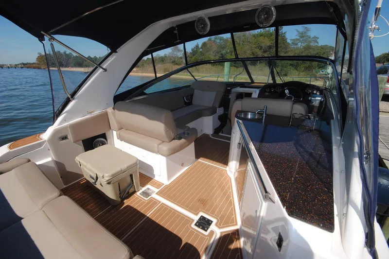 Slide: The Image of 2015 Regal 32 Express boat interior with seating, kitchenette, and steering area on a sunny day. - 5