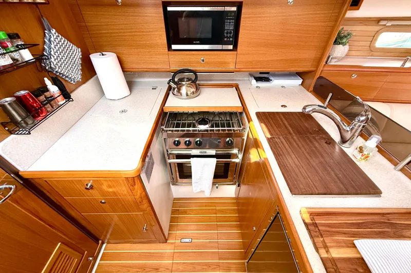 Slide: The Image of Modern Catalina 425 yacht kitchen with wooden cabinetry, stainless steel appliances, and ample counter space, 2020 model. - 31