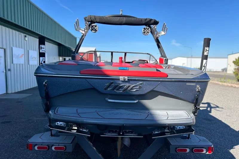 Slide: The Image of 2018 Tigé R20 boat with red seating, parked outside a warehouse on a sunny day. - 11