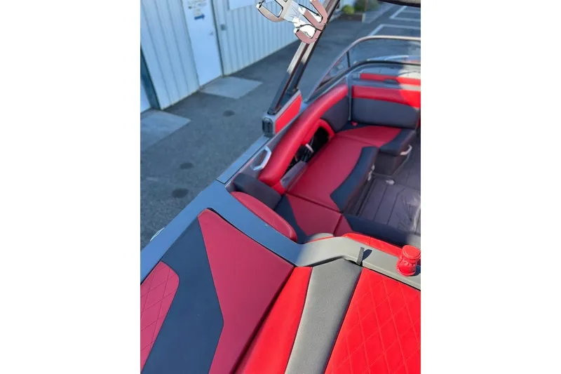 Slide: The Image of 2018 Tigé R20 boat interior with red and black seating, docked near a building. - 18