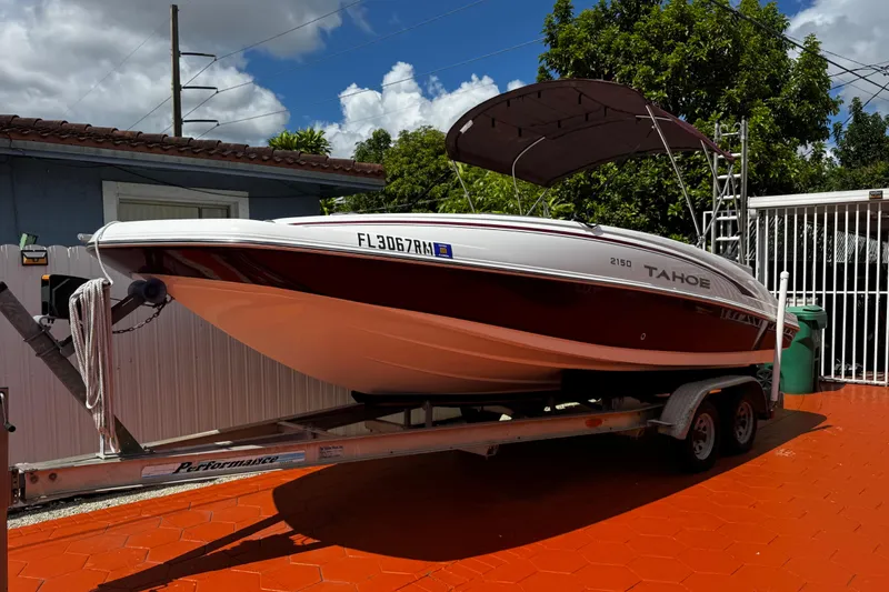 The Image of 2017 Tahoe 2150 boat on trailer, parked in driveway under a cloudy sky. - 1