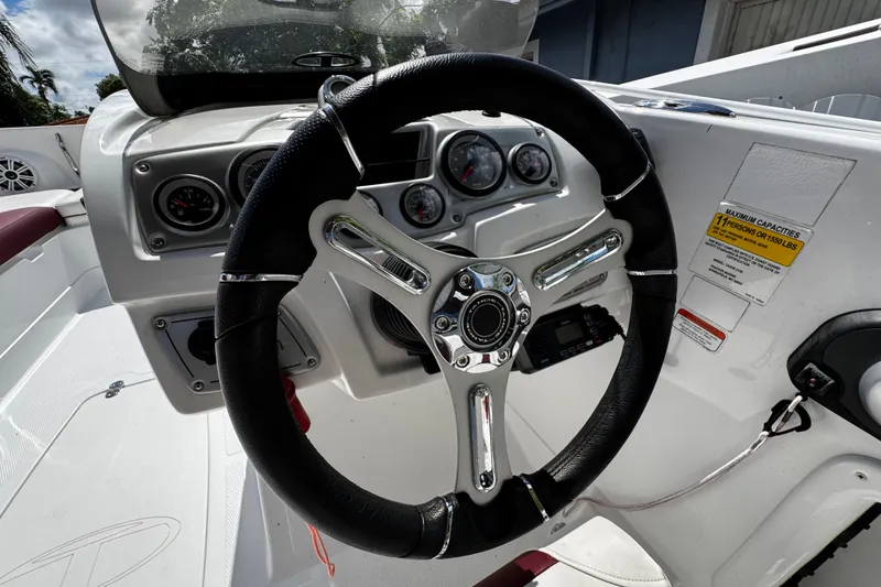 Slide: The Image of Steering wheel and dashboard of a 2017 Tahoe 2150 boat, featuring gauges and controls. - 17
