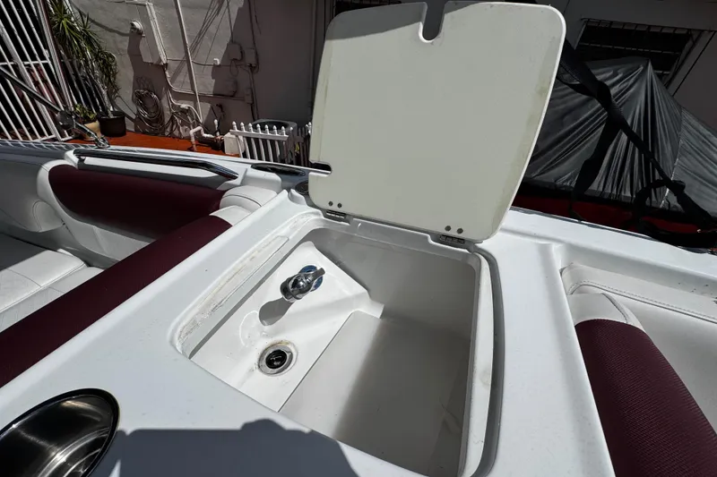 Slide: The Image of 2017 Tahoe 2150 boat interior with open storage compartment and maroon seating. - 28