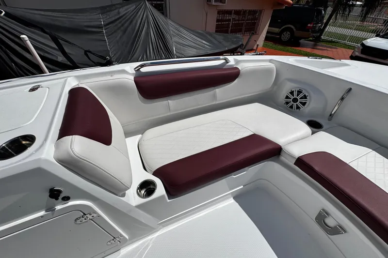 Slide: The Image of 2017 Tahoe 2150 boat interior with maroon and white seating, cup holders, and speaker. - 32