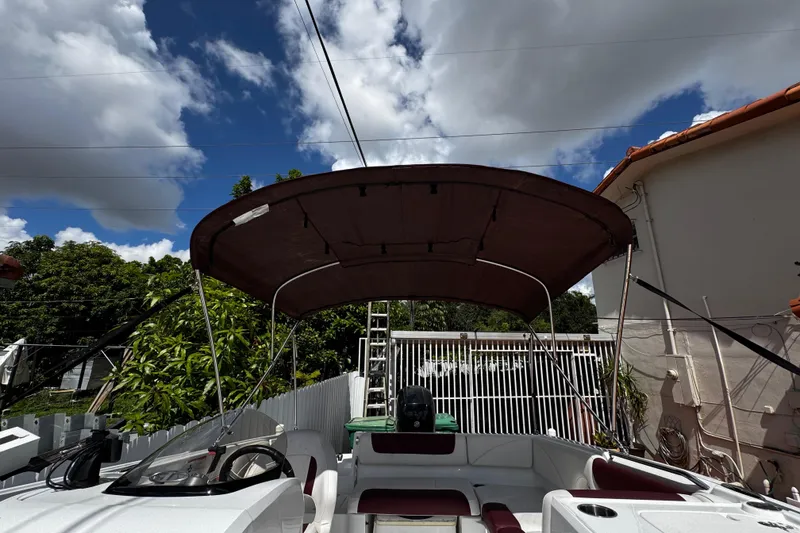Slide: The Image of 2017 Tahoe 2150 boat with canopy, parked outdoors under a partly cloudy sky. - 36