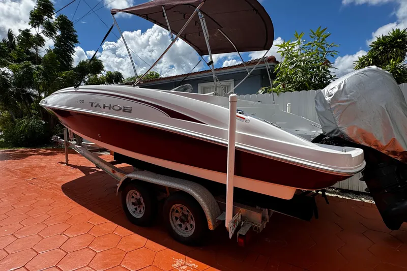 Slide: The Image of 2017 Tahoe 2150 boat on trailer, red and white, parked outdoors under blue sky. - 6