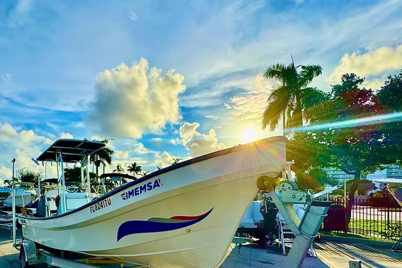 Slide: The Image of 2024 Panga 25 CC boat on trailer, sunny day, palm trees, vibrant sky. - 2