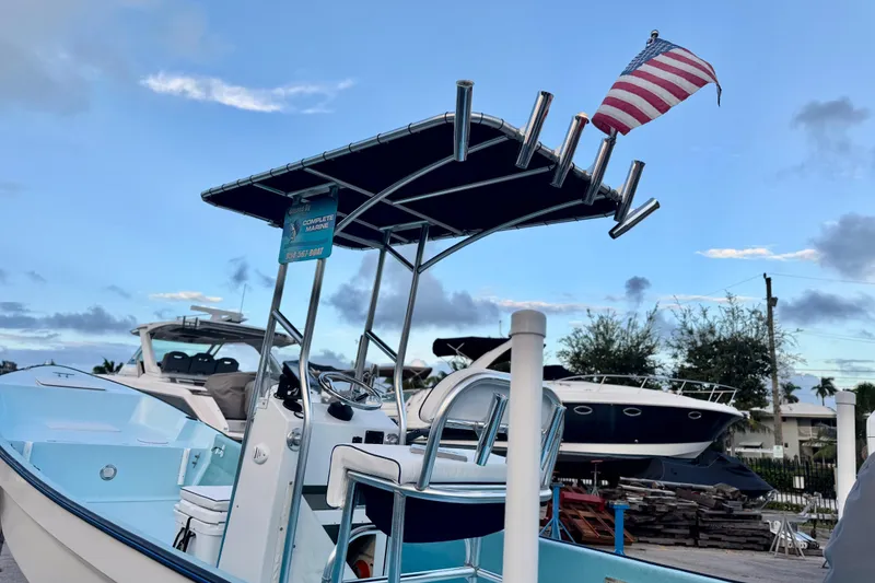 Slide: The Image of 2024 Panga 25 CC boat with T-top and American flag, docked under a blue sky. - 40