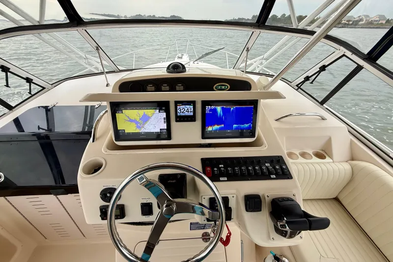 Slide: The Image of 2005 Grady-White Express 330 helm with navigation screens and steering wheel on open water. - 18