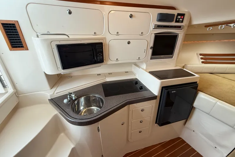Slide: The Image of 2005 Grady-White Express 330 boat interior with kitchenette, sink, microwave, and compact fridge. - 28