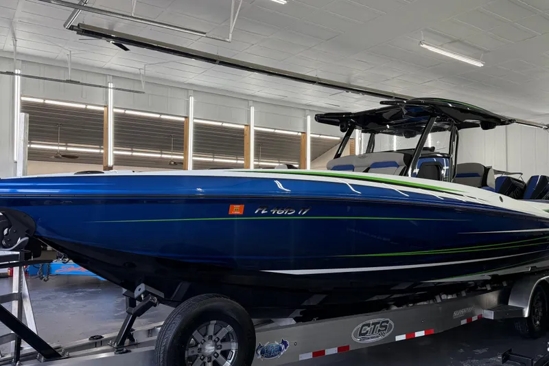 Slide: The Image of 2025 Sunsation 32 CCX boat in showroom, blue with green accents, on trailer. - 3