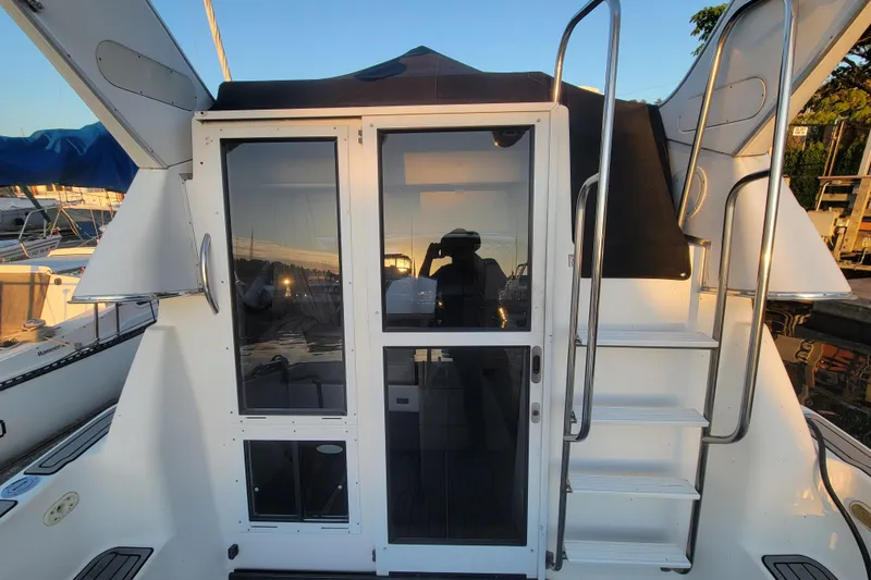 Slide: The Image of 1998 Bayliner 2858 Ciera Command Bridge with rear entry and ladder, docked at sunset. - 11
