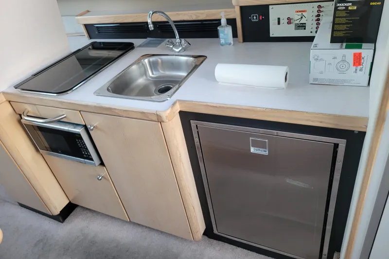 Slide: The Image of 1998 Bayliner 2858 Ciera Command Bridge kitchen with sink, microwave, and fridge. - 18