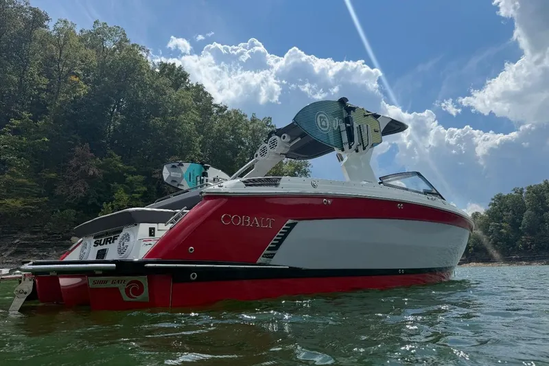 Slide: The Image of 2021 Cobalt R8 Surf boat in red and white on a trailer, parked outside. - 2