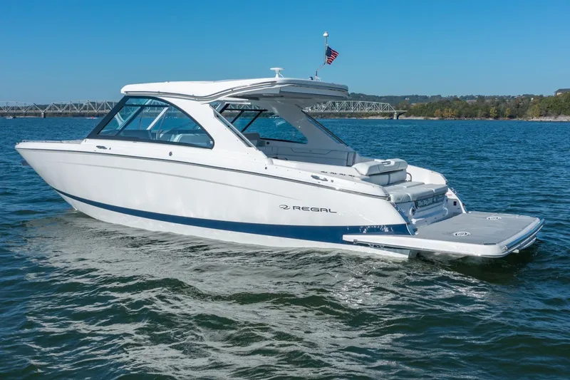 Slide: The Image of 2023 Regal LS36 boat cruising on a sunny day, with bridge in background. - 2