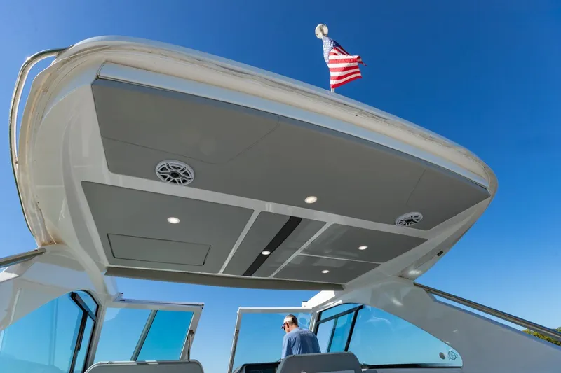 Slide: The Image of 2023 Regal LS36 boat with American flag, sleek design, and modern features under clear blue sky. - 20