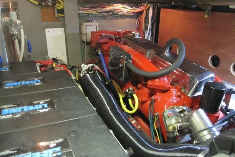 Slide: The Image of Engine room of a 1983 Nauticat 43 sailboat, featuring a red engine and wiring. - 20