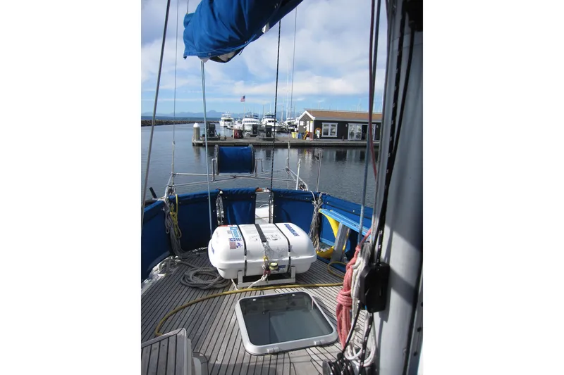 Slide: The Image of 1983 Nauticat 43 sailboat deck view at marina, featuring blue canopy and lifeboat. - 27