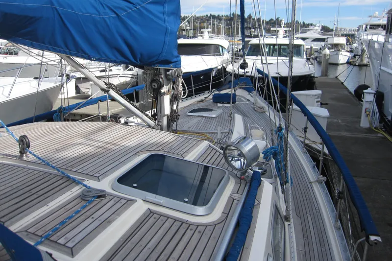 Slide: The Image of 1983 Nauticat 43 sailboat docked at marina, featuring wooden deck and blue sail cover. - 34