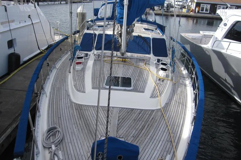 Slide: The Image of 1983 Nauticat 43 sailboat docked, featuring a sleek wooden deck and blue accents. - 37