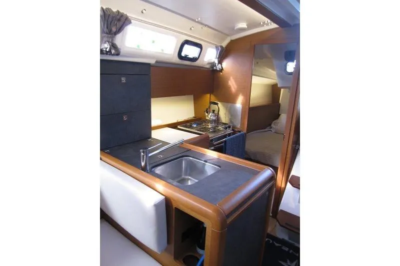 Slide: The Image of Interior of 2022 Jeanneau Sun Odyssey 349 yacht, featuring a compact kitchen and cozy cabin. - 14