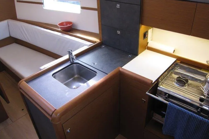 Slide: The Image of Interior of 2022 Jeanneau Sun Odyssey 349 yacht, featuring a compact kitchen with sink and stove. - 3