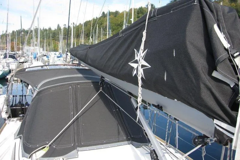 Slide: The Image of 2022 Jeanneau Sun Odyssey 349 sailboat with black sail cover in marina. - 42