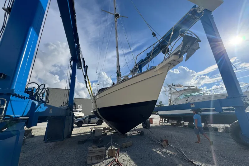 Slide: The Image of Island Packet 380 sailboat from 2000 in a boatyard lift under a bright sky. - 14