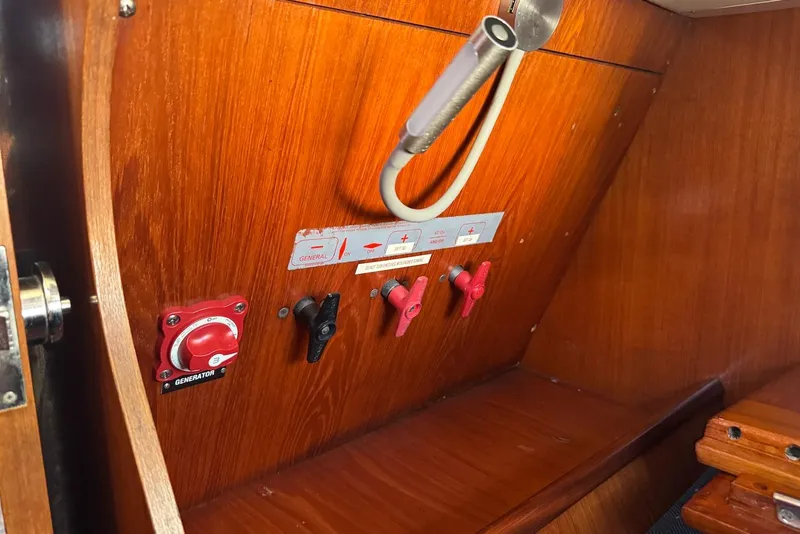 Slide: The Image of Control panel inside a 1992 Beneteau Oceanis 370 sailboat, featuring switches and a generator knob. - 32