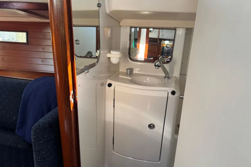 Slide: The Image of Interior of 1992 Beneteau Oceanis 370 yacht, featuring a compact bathroom with sink and mirror. - 38