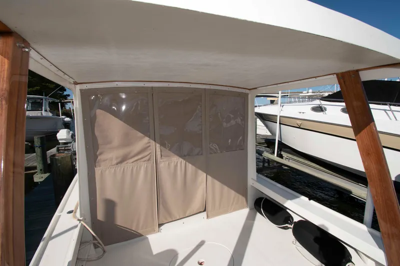 Slide: The Image of 1982 Nauset 27 Downeast Cruiser interior with protective canvas cover, docked beside other boats. - 10