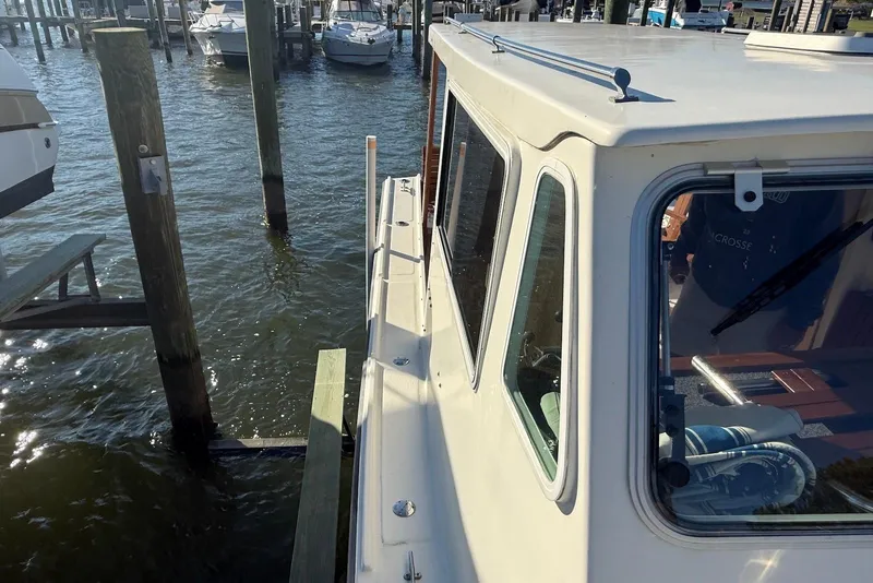 Slide: The Image of 1982 Nauset 27 Downeast Cruiser docked at marina, showcasing cabin and water reflections. - 11