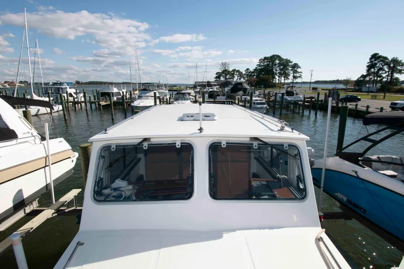 Slide: The Image of 1982 Nauset 27 Downeast Cruiser docked at a marina under a clear blue sky. - 12