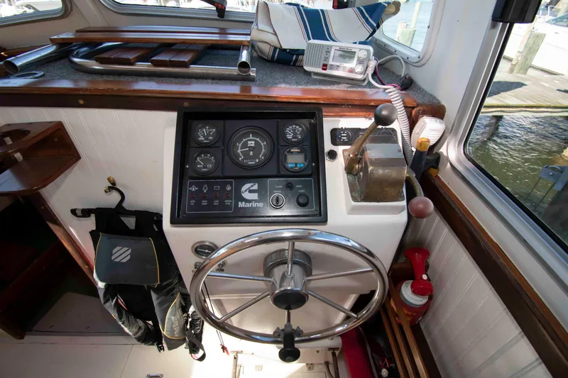 Slide: The Image of 1982 Nauset 27 Downeast Cruiser helm with steering wheel, gauges, and marine radio. - 17