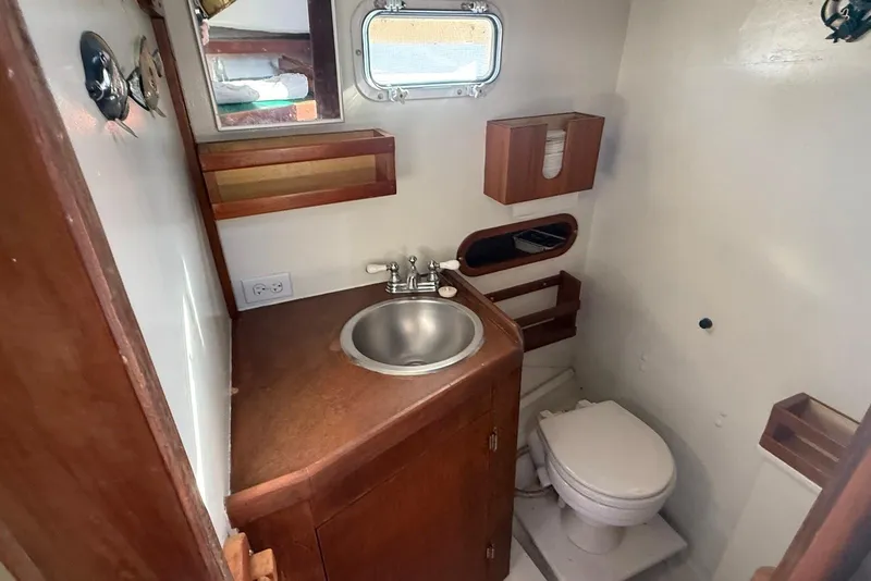 Slide: The Image of 1982 Nauset 27 Downeast Cruiser bathroom with sink, toilet, and wooden cabinetry. - 20