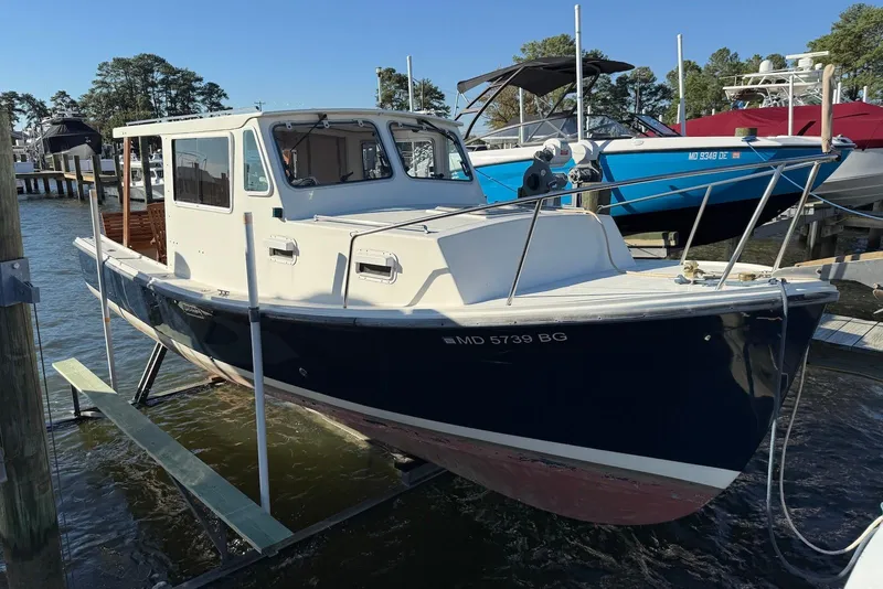 Slide: The Image of 1982 Nauset 27 Downeast Cruiser docked at marina, blue and white hull. - 4