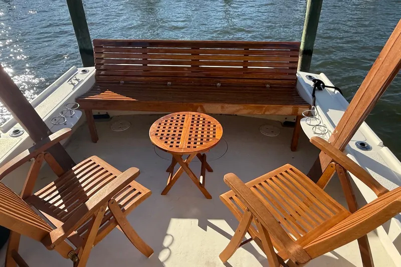 Slide: The Image of 1982 Nauset 27 Downeast Cruiser with wooden seating and table on deck by the water. - 8