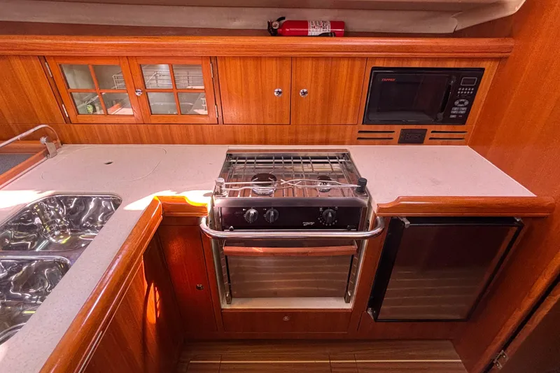 Slide: The Image of Galley kitchen in 2006 Hunter 38 yacht with stove, microwave, and wooden cabinetry. - 46