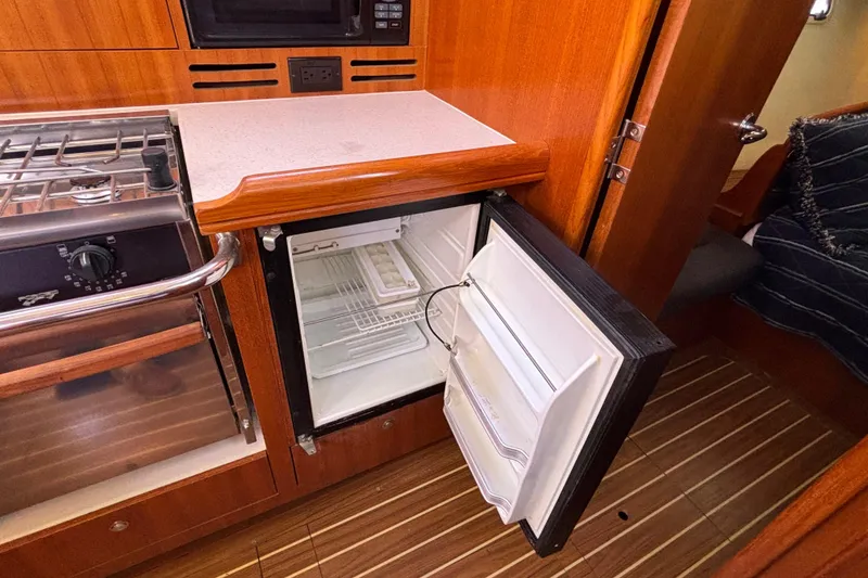 Slide: The Image of Small refrigerator in 2006 Hunter 38 yacht kitchen, open door, wooden cabinetry. - 50