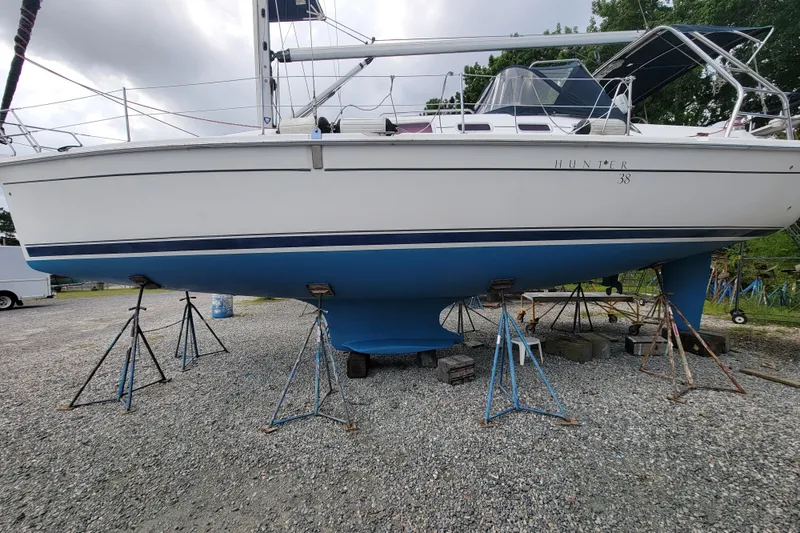 Slide: The Image of 2006 Hunter 38 sailboat on stands, white hull with blue bottom, overcast sky. - 72
