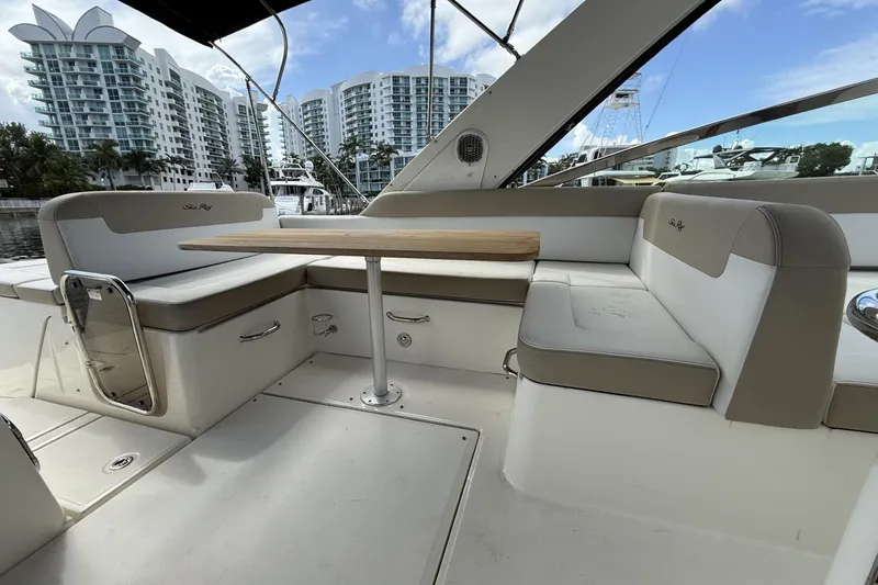 Slide: The Image of 2015 Sea Ray 370 Venture yacht interior with seating and table, docked near modern buildings. - 16