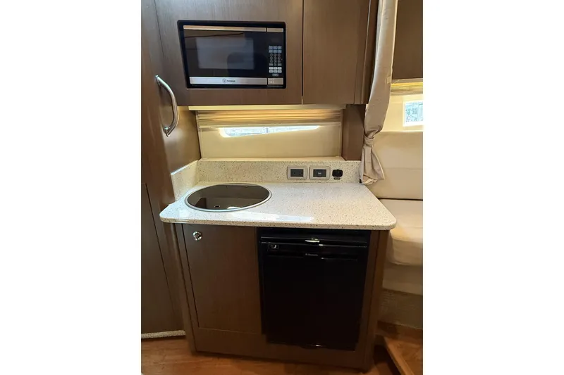 Slide: The Image of 2015 Sea Ray 370 Venture galley with microwave, cooktop, and compact fridge. - 24