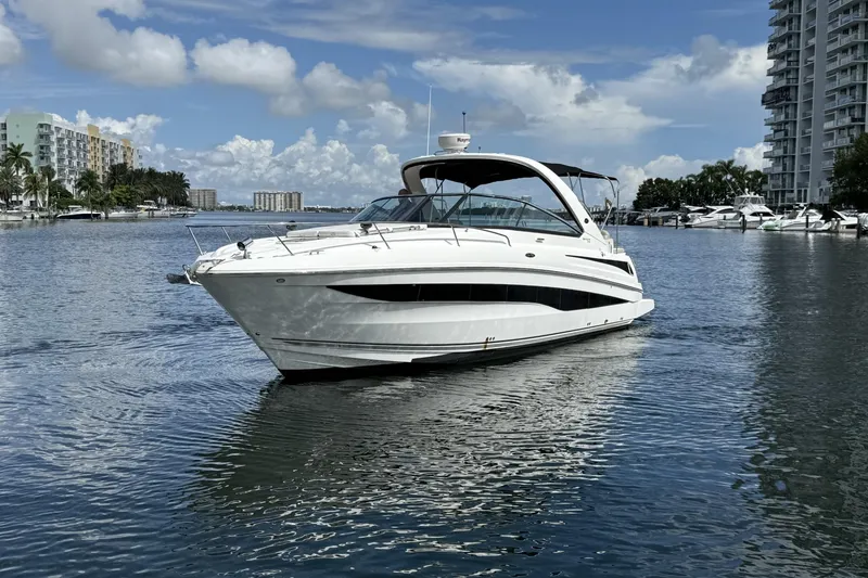 Slide: The Image of 2015 Sea Ray 370 Venture yacht on calm water, surrounded by buildings and palm trees. - 5
