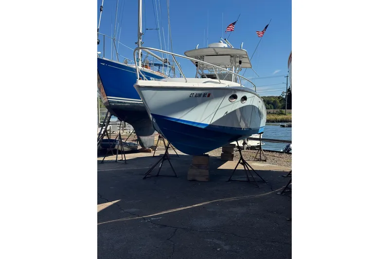 Slide: The Image of 1990 Donzi F 33 boat on stands, dockside with flags, clear sky. - 1