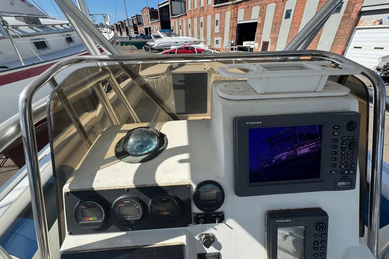 Slide: The Image of 1990 Donzi F 33 boat dashboard with navigation equipment and gauges in a marina setting. - 10