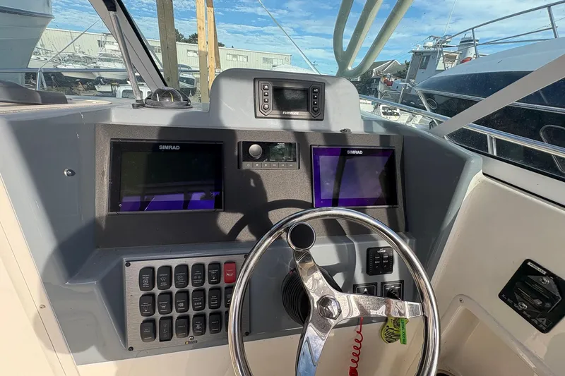 Slide: The Image of 2018 Striper 230 Walkaround boat dashboard with Simrad displays and steering wheel. - 16