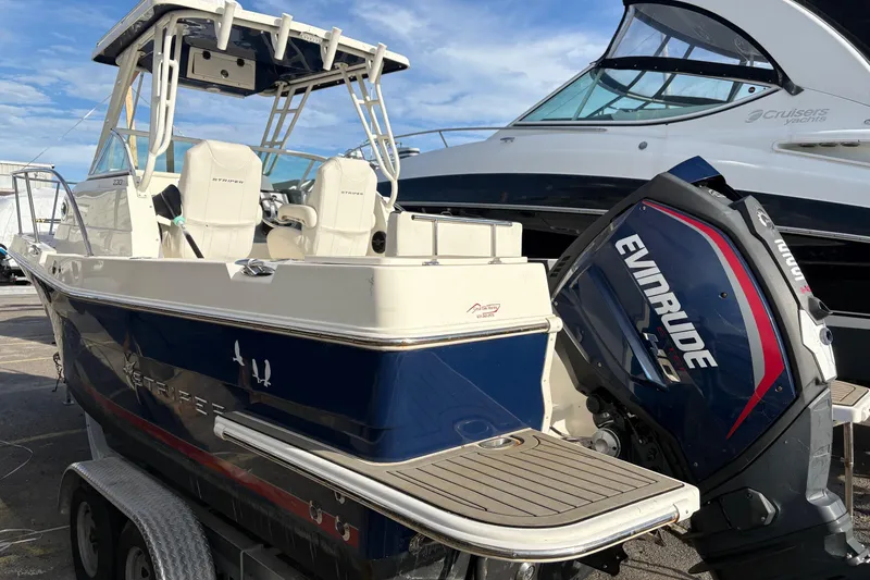 Slide: The Image of 2018 Striper 230 Walkaround boat with Evinrude engine, parked on a trailer. - 3