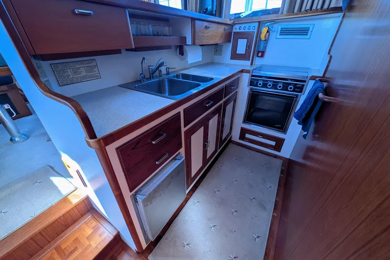 Slide: The Image of Compact kitchen in a 2001 Dettling 51 yacht, featuring wood cabinetry and modern appliances. - 27