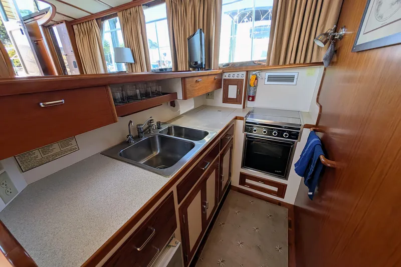 Slide: The Image of Compact kitchen in a 2001 Dettling 51 yacht with wood cabinetry and stainless steel sink. - 30